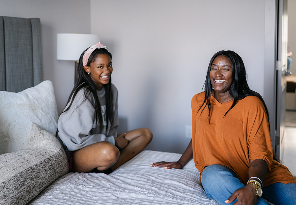 friends smiling on bed